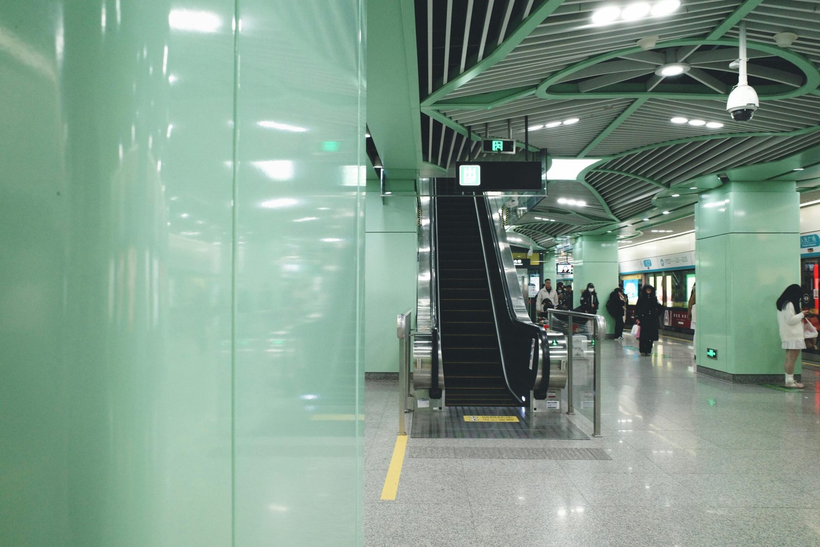 Spacious modern subway station featuring an escalator and people, highlighting urban transit design.