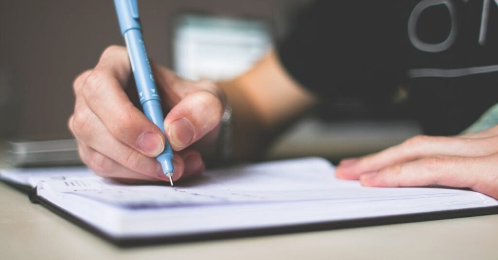 pexels photo 210661 210661 Close-up of hand writing in notebook using a blue pen, focus on creativity.