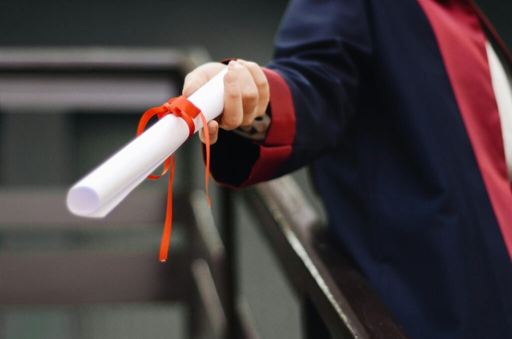 pexels photo 2292837 2292837 1 A close-up image of a graduate holding a diploma tied with a red ribbon, symbolizing achievement and success.