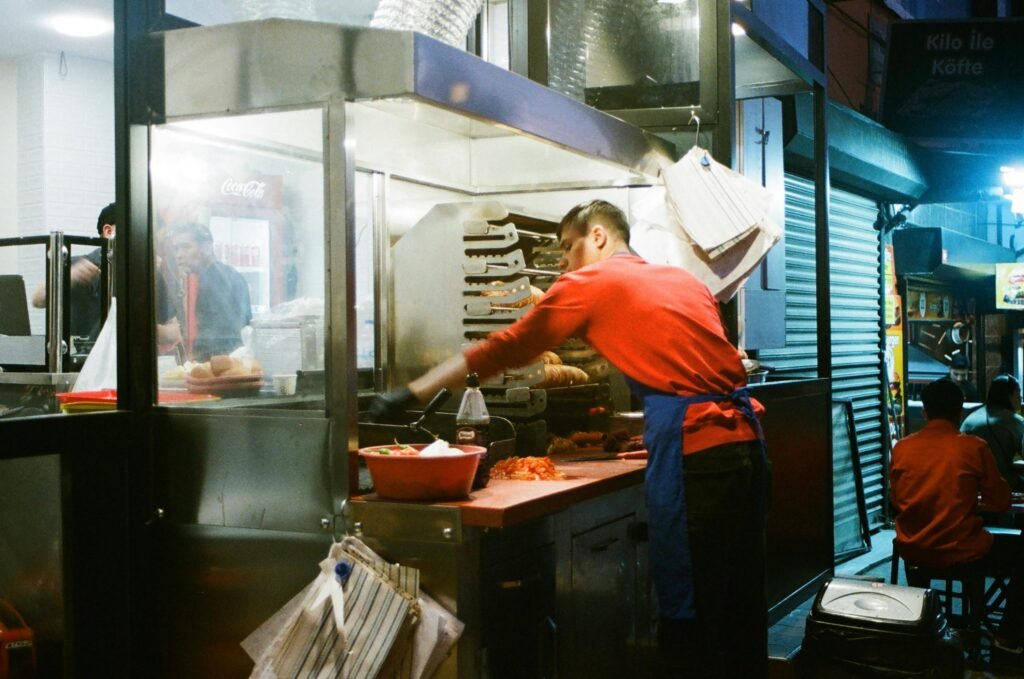 pexels-photo-12276940-12276940 Street vendor preparing food at a night market, showcasing culinary skil how to succeed academically as a night-shift workerls in a lively stall.