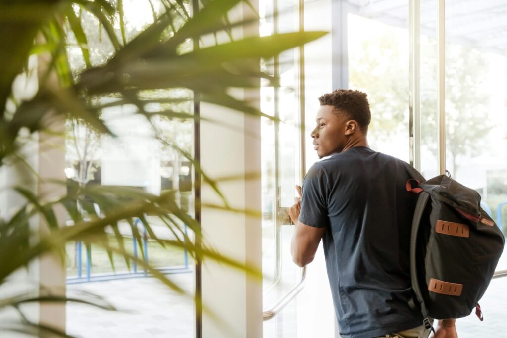 pexels-photo-1251861-1251861 A college student with a backpack exits a campus building through glass doors. (re-apply to university after dropping out)