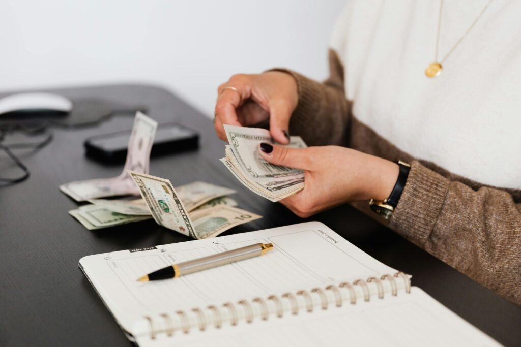 pexels photo 4475523 4475523 Close-up of person counting cash with notepad on desk, indicating financial tasks.