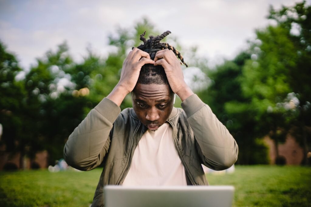 pexels photo 4560092 4560092 Upset young African American male freelancer clutching head with hands after failure in project while working remotely in park