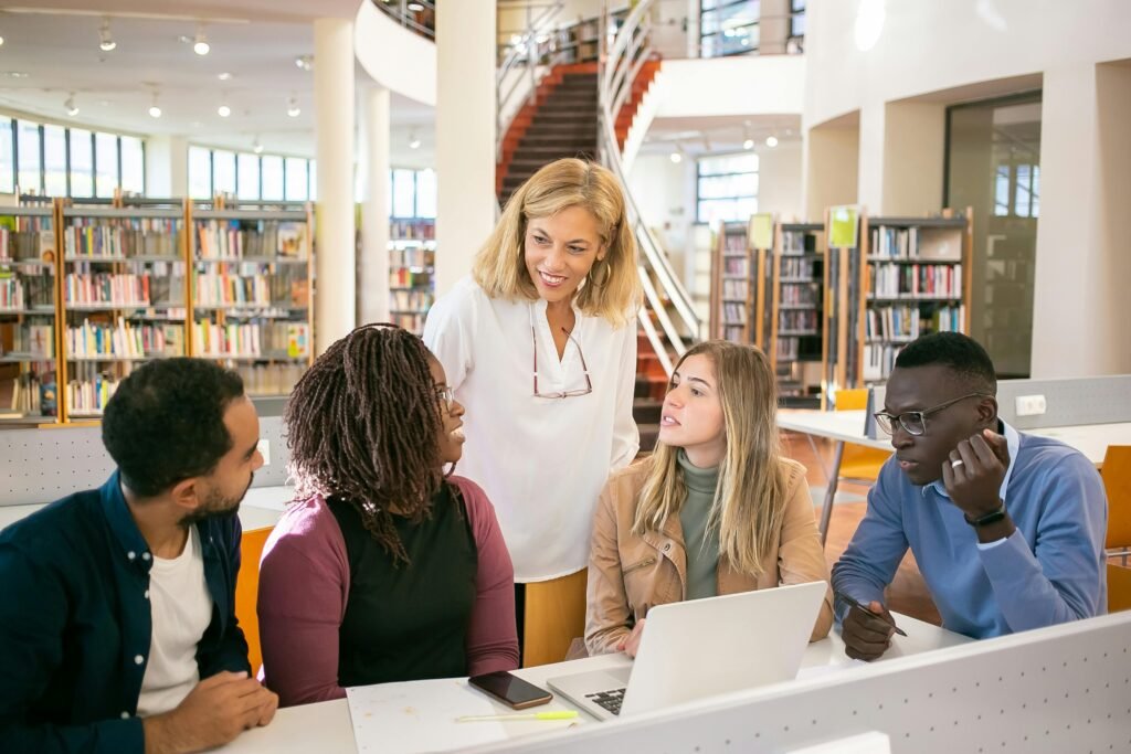 pexels photo 5940827 5940827 A diverse group of students collaborating with a teacher in a modern library setting.