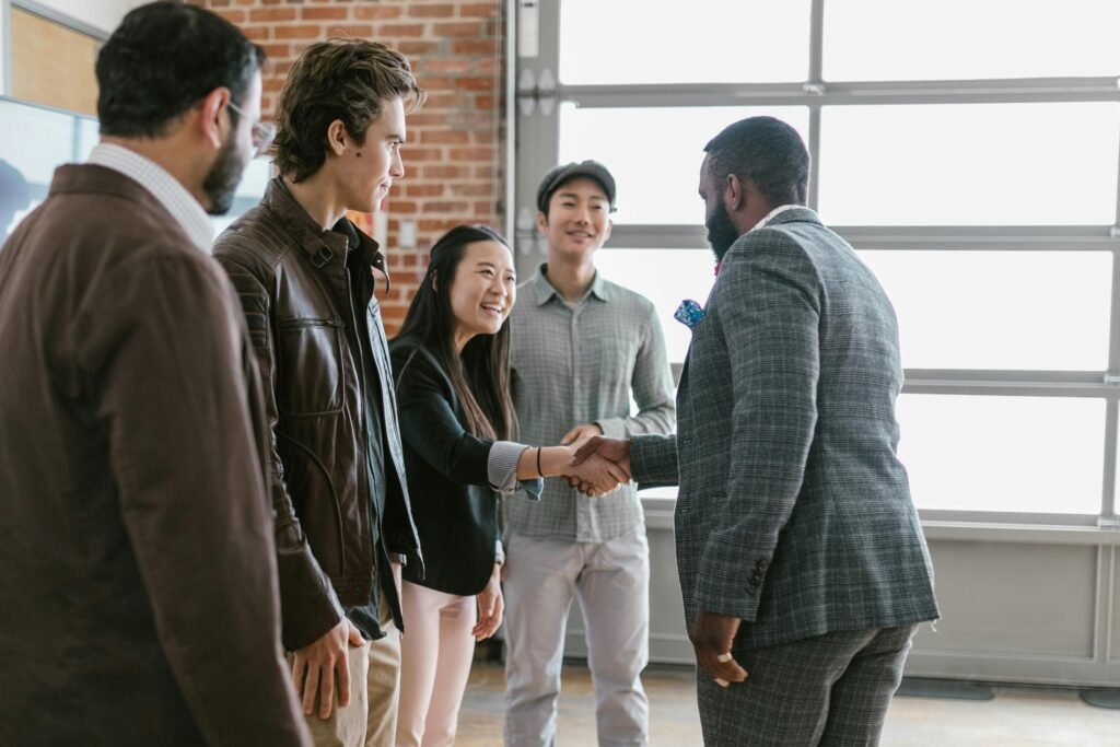 pexels photo 7414275 7414275 A diverse group of college students networking engaging in a handshake and discussion in a modern office space.