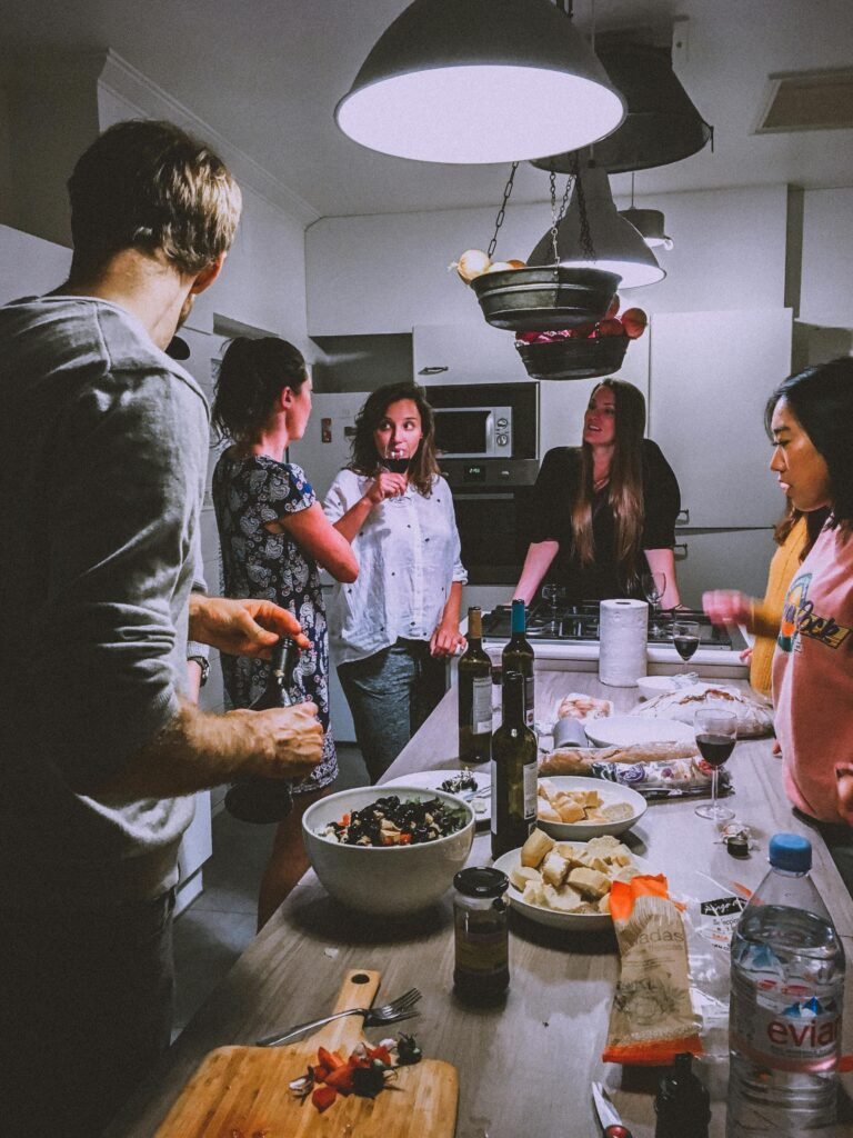 A group of adults enjoying a casual dinner party in a cozy, modern kitchen setting.