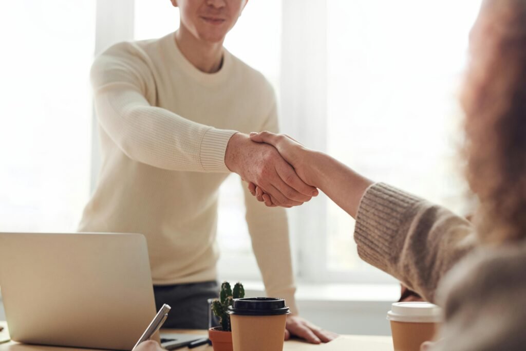 Close-up of professionals in an interview shaking hands over coffee in a modern office.