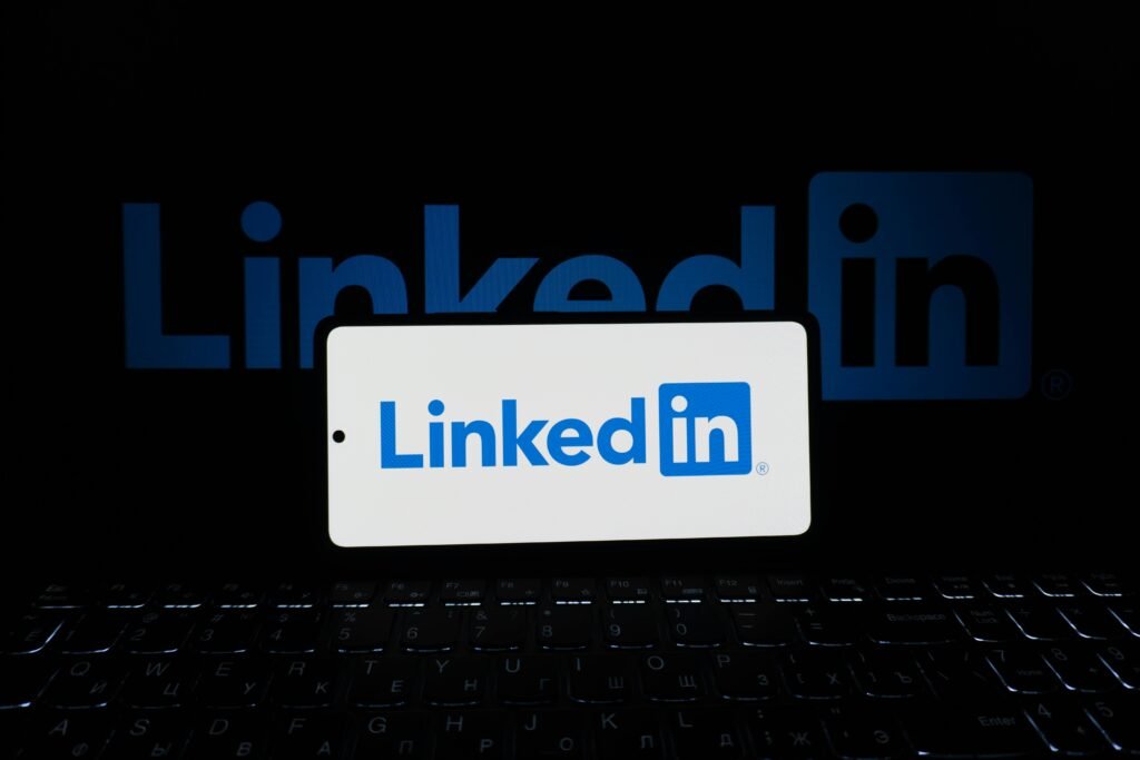 pexels-photo-33440526-33440526 Smartphone showing LinkedIn logo with keyboard and large background logo, business theme.