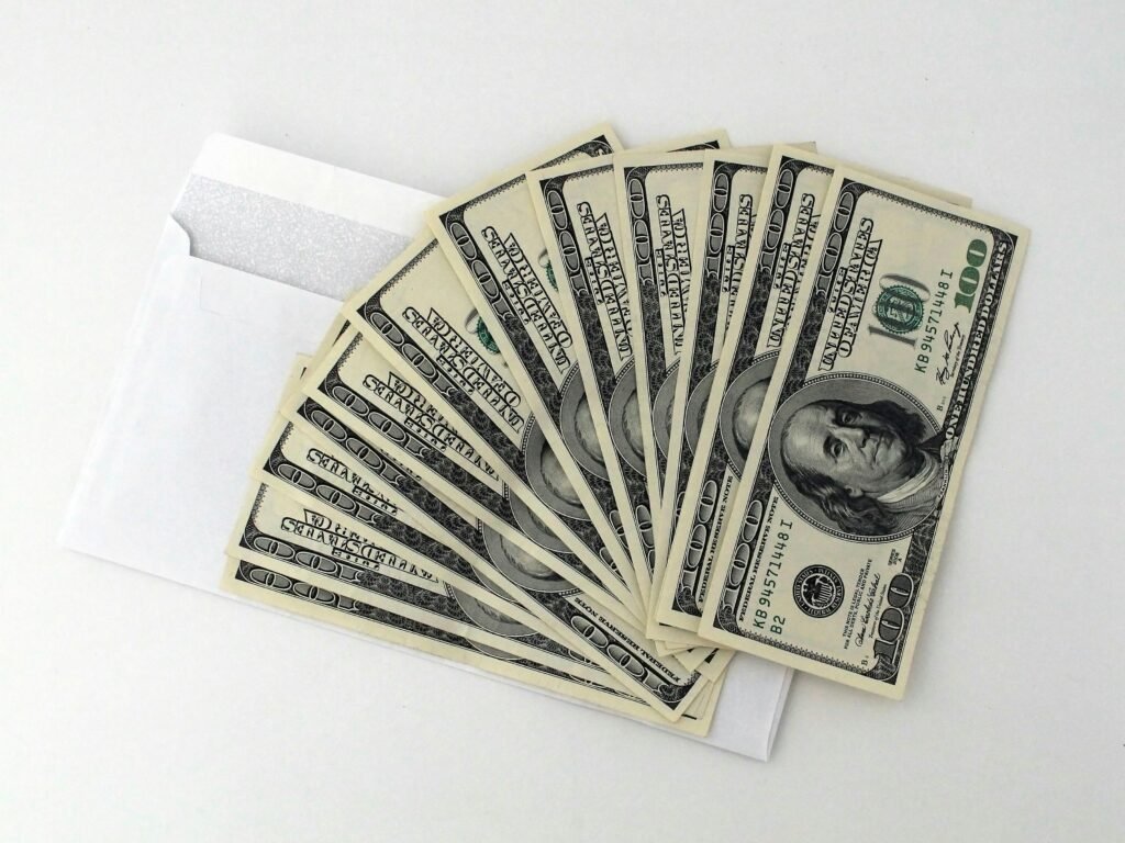 pexels-photo-534229-534229 Fan of US $100 bills partially out of a white envelope on a white background.
