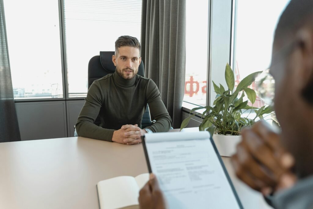 Professional man in turtleneck at office desk during a job interview.