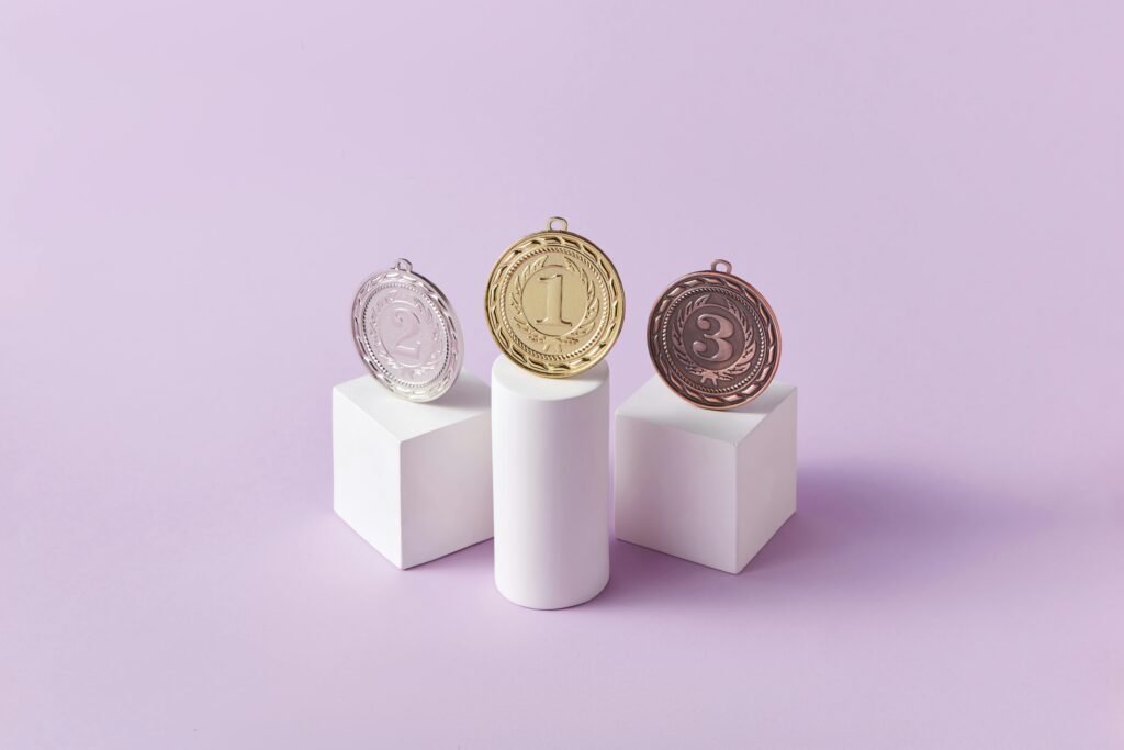 pexels-photo-7267591-7267591 top universities Gold, silver, and bronze medals displayed on white pedestals with a pink background.