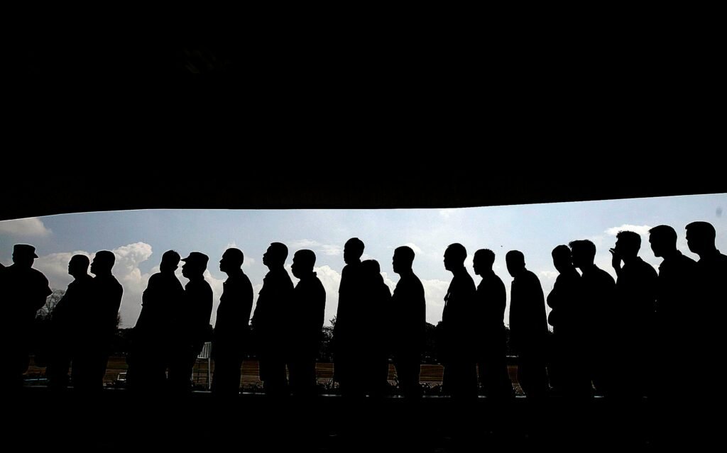 pexels-photo-761295-761295 Silhouettes of people in line under a shaded canopy, highlighting social interaction and society.